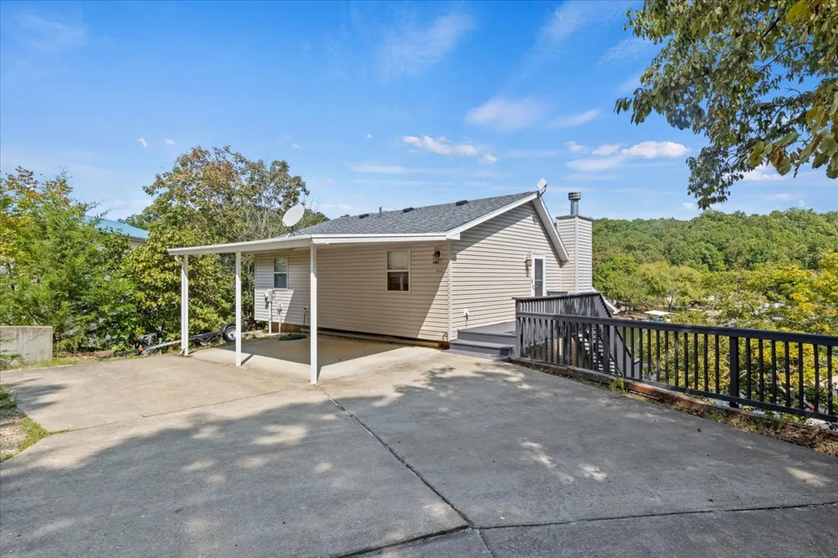 This exterior image highlights the welcoming porch area nestled among mature trees and a private driveway. The scene conveys a sense of seclusion and tranquility, with the home surrounded by nature and no visible neighbors or distractions. The driveway's incline and the enveloping greenery reinforce the exclusive, elevated feeling described in the section.