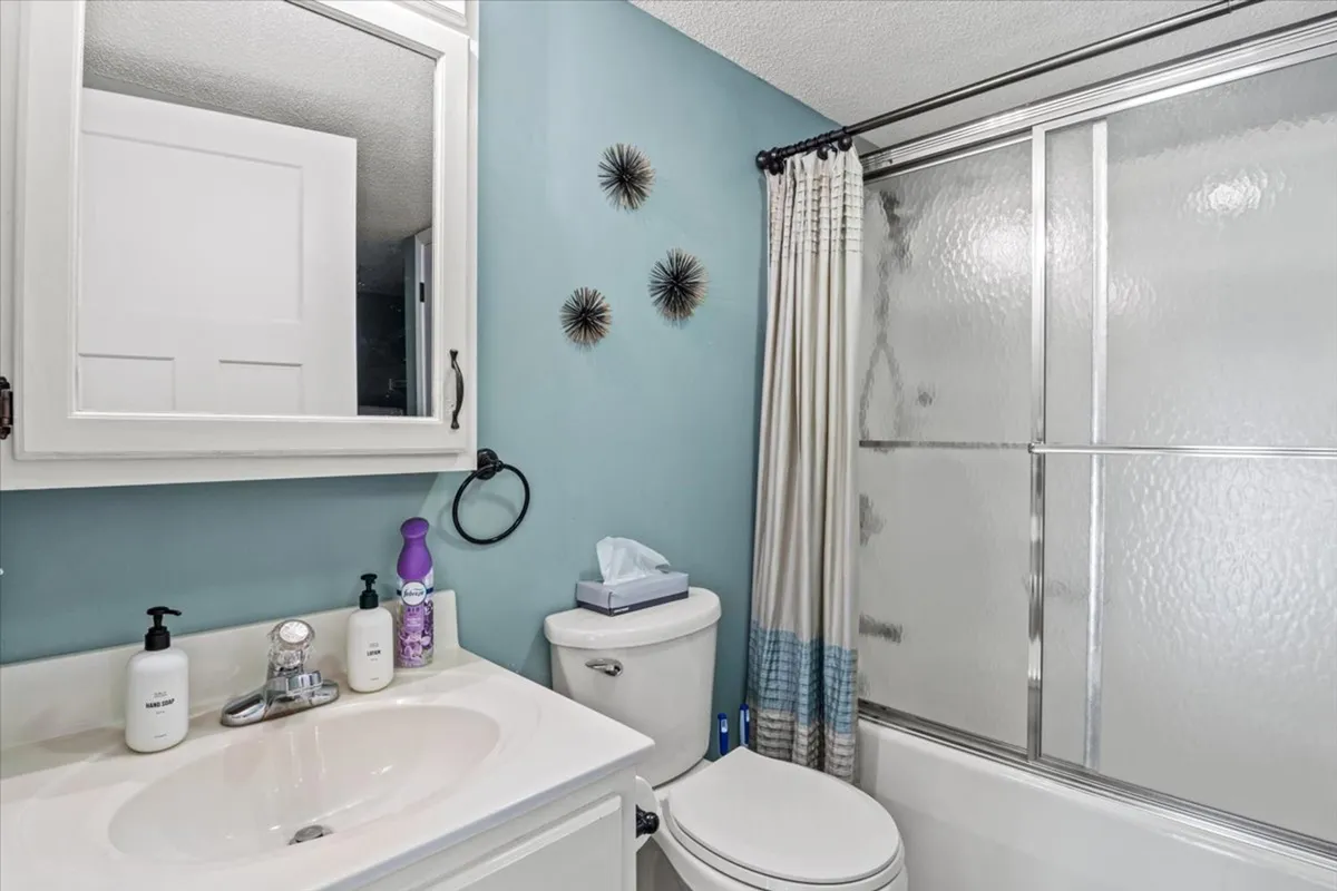 A modern bathroom featuring a spacious sink with a large mirror, a sleek shower area, and decorative wall pieces. The space is bright, clean, and designed for relaxation or refreshing routines.