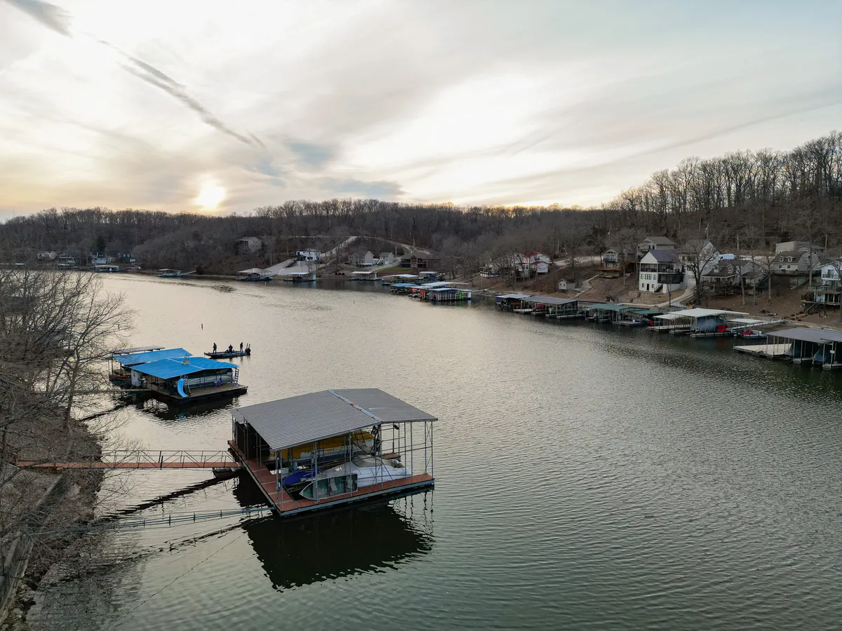 A peaceful exterior view of the lake dotted with boats, waterfront houses, and lush trees. The perspective hints at the vibrant lake community and the array of water-based activities available, from fishing to family gatherings by the shore.