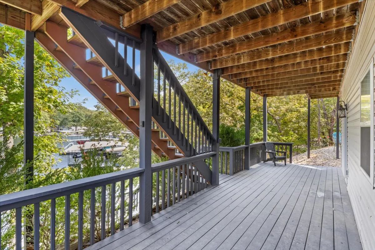 This exterior shot captures wooden stairs and a deck railing overlooking water and encircled by forest. The vantage point provides both a sense of elevation and immersion in nature. With glimpses of the water and the surrounding trees, the image conveys a serene, resort-like environment just steps from the house.