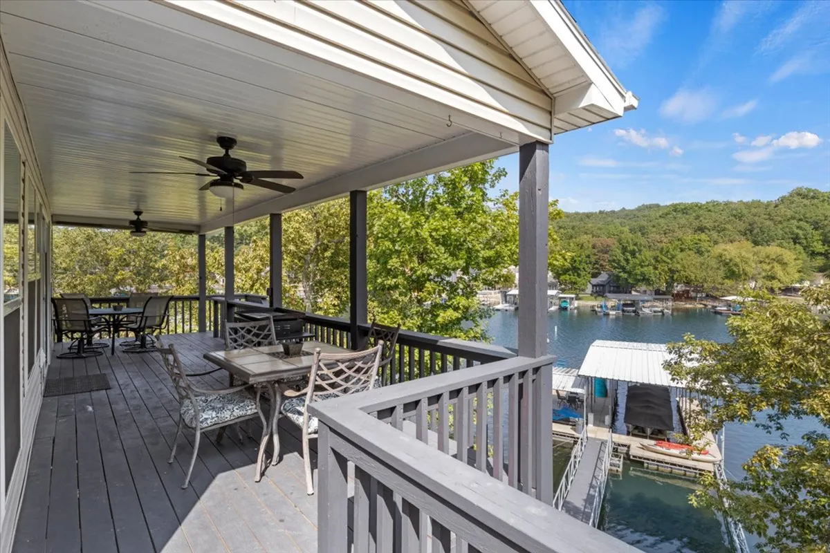 This image showcases an outdoor dining area set against the backdrop of a tranquil lake and surrounded by lush trees. The table is situated on a spacious deck, ideal for group meals, relaxed gatherings, and soaking in nature. The clear lake view and greenery create a sense of peace and connection with the outdoors.