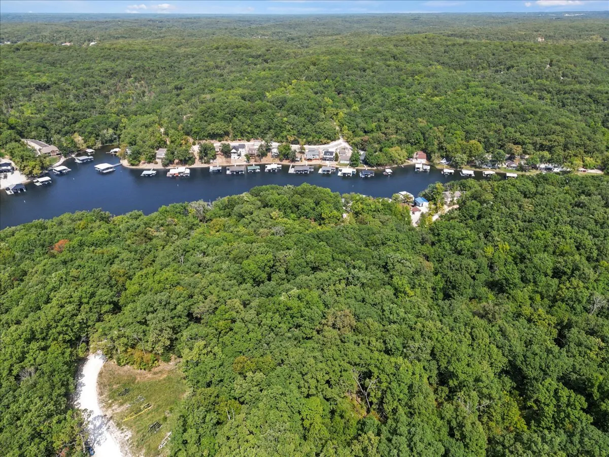 A broad, sweeping view of the green forest, tranquil waterway, marina, and residential units along the water. This vantage gives a sense of the broader setting—serene, natural, and removed from crowds—while also alluding to the range of curated experiences available nearby, from boating to quiet reflection.